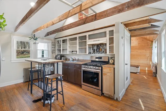 a kitchen with stainless steel appliances granite countertop a stove and a dining table with wooden floor