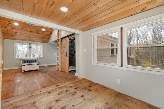 a view of an empty room with a window and wooden floor