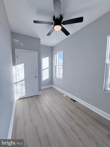 an empty room with wooden floor cabinet and windows