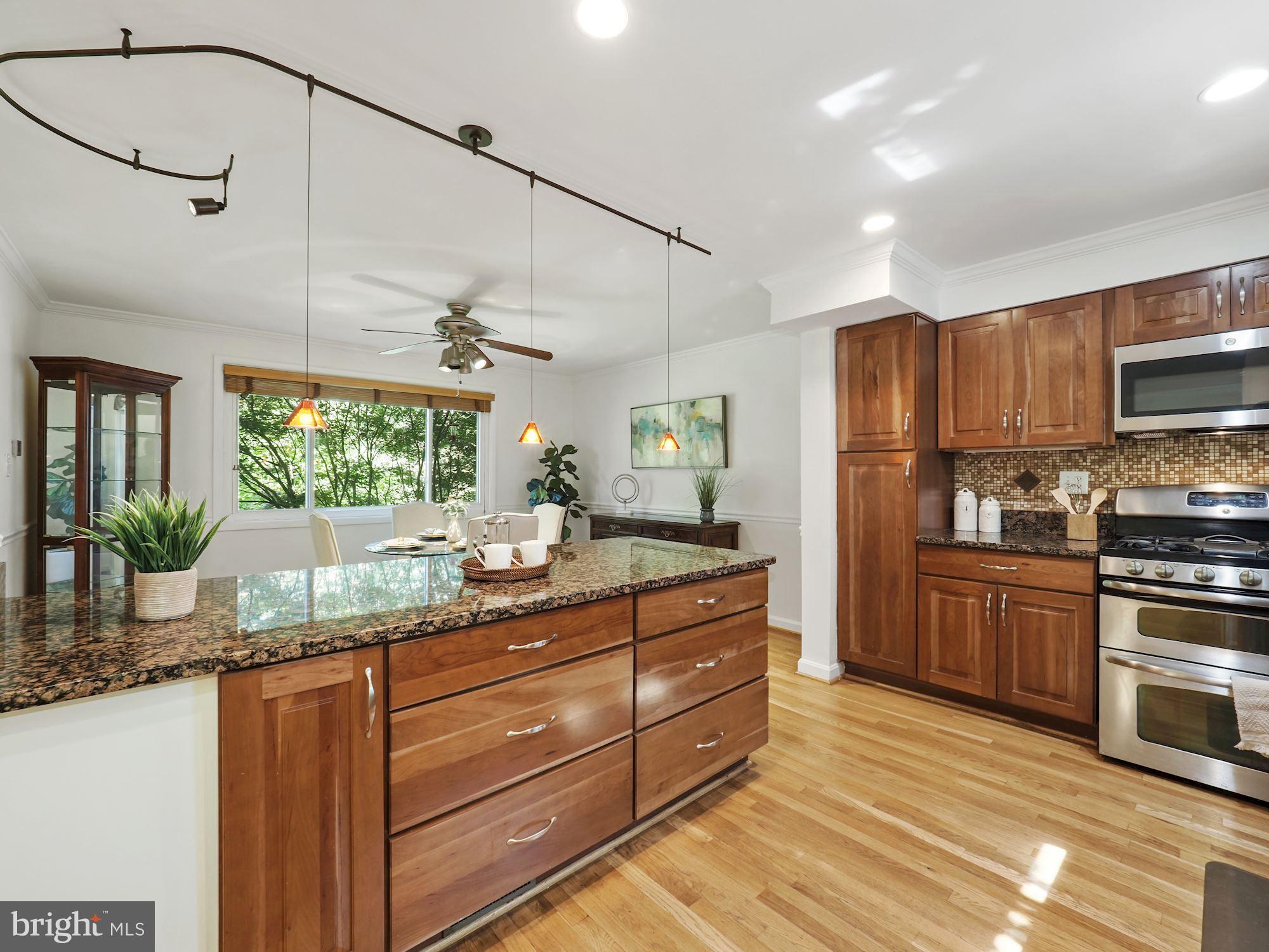 5343 Pooks Hill Road, Unit 40353 Bethesda, MD 20814 - Photo 11 of 57 a kitchen with kitchen island granite countertop wooden cabinets and white appliances