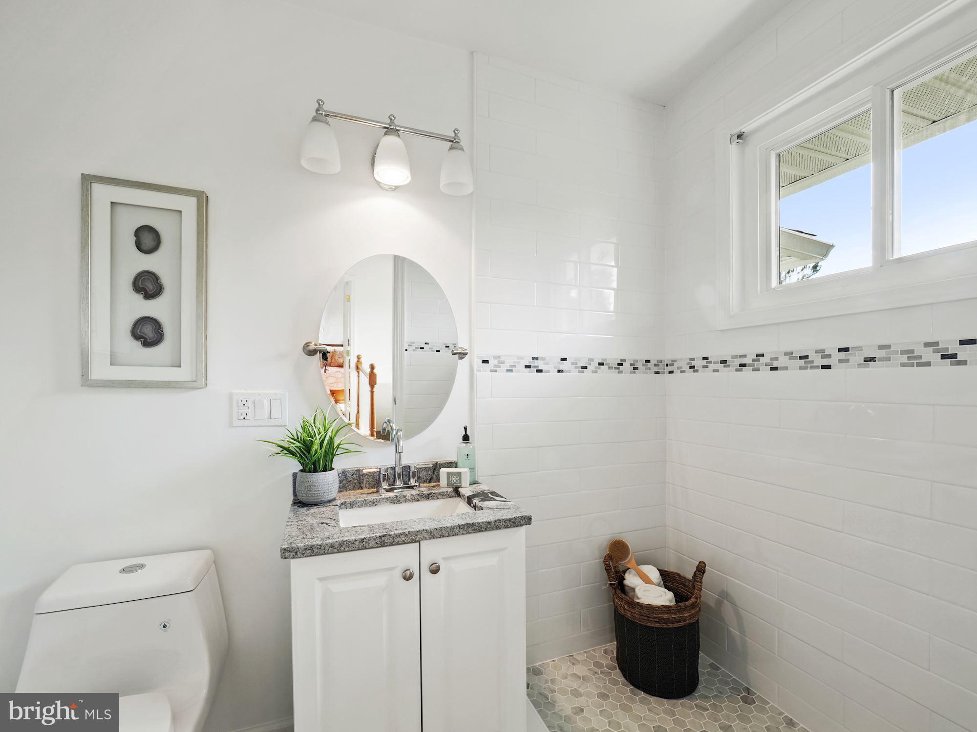 5343 Pooks Hill Road, Unit 40353 Bethesda, MD 20814 - Photo 19 of 57 a bathroom with a granite countertop sink a toilet and mirror