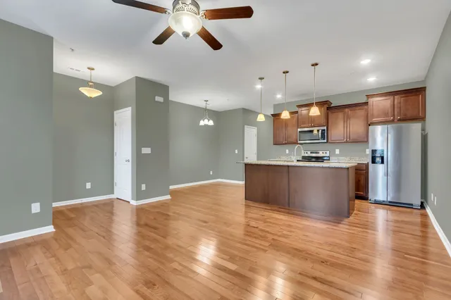 a large kitchen with stainless steel appliances kitchen island a refrigerator sink a stove and a oven with wooden floor