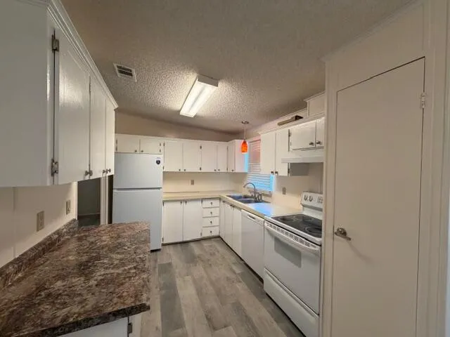a kitchen with a sink a refrigerator and white cabinets