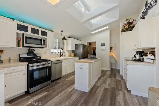 a kitchen with a sink wooden floor and white stainless steel appliances