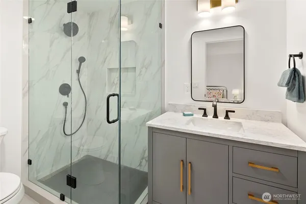 a bathroom with a shower sink vanity mirror and toilet