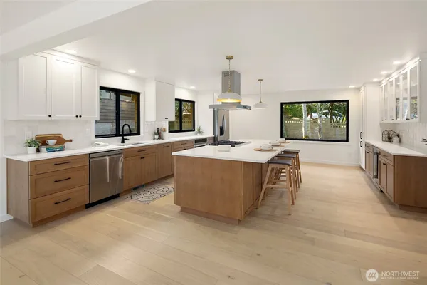 a large white kitchen with stainless steel appliances kitchen island granite countertop a sink and cabinets