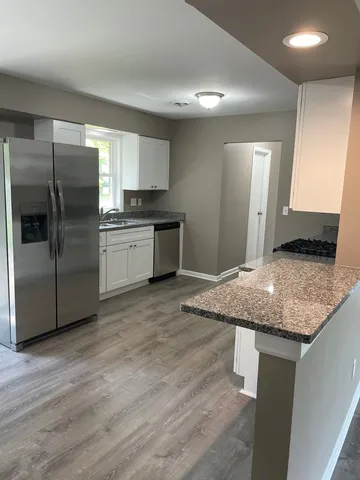 a kitchen with stainless steel appliances granite countertop a refrigerator and a stove top oven
