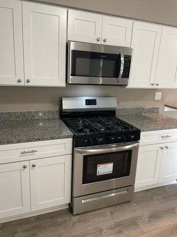 a kitchen with granite countertop white cabinets stainless steel appliances and sink