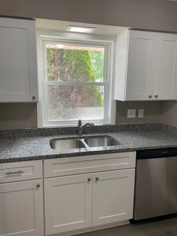 a kitchen with granite countertop white cabinets and a window