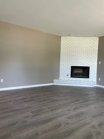 a view of empty room with wooden floor and fireplace