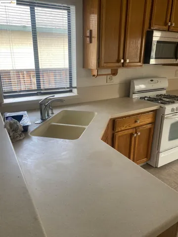 a kitchen with stainless steel appliances granite countertop a sink and a stove next to a window