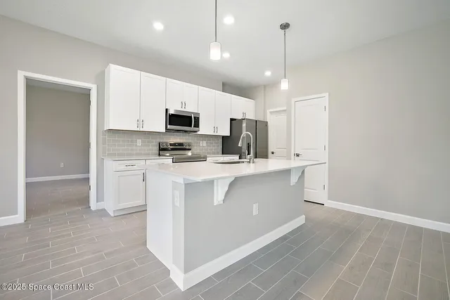 a kitchen with kitchen island white cabinets and stainless steel appliances