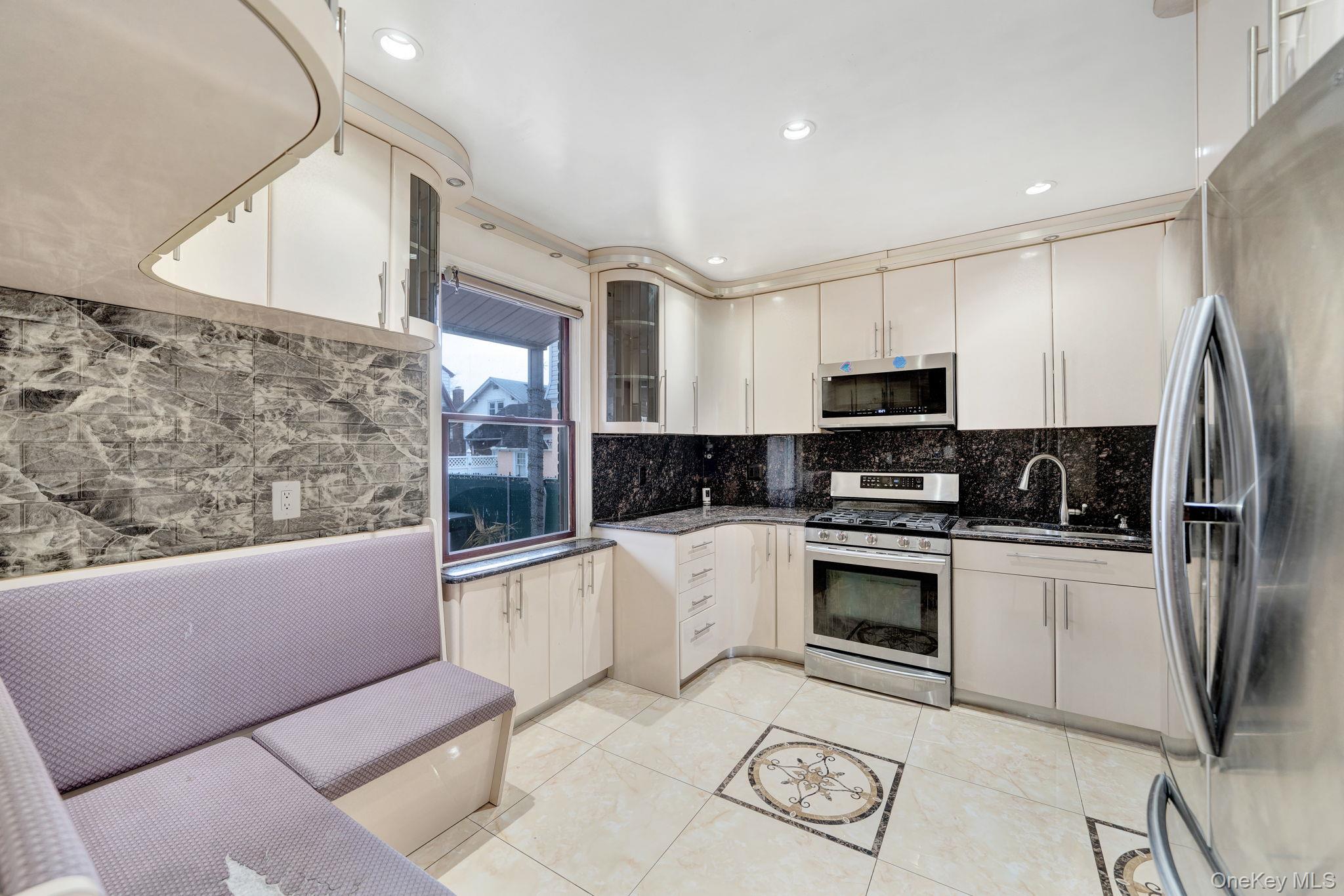 87-67 Chevy Chase Street Queens, NY 11432 - Photo 12 of 31 a kitchen with stainless steel appliances granite countertop a refrigerator a stove and a sink with wooden floor