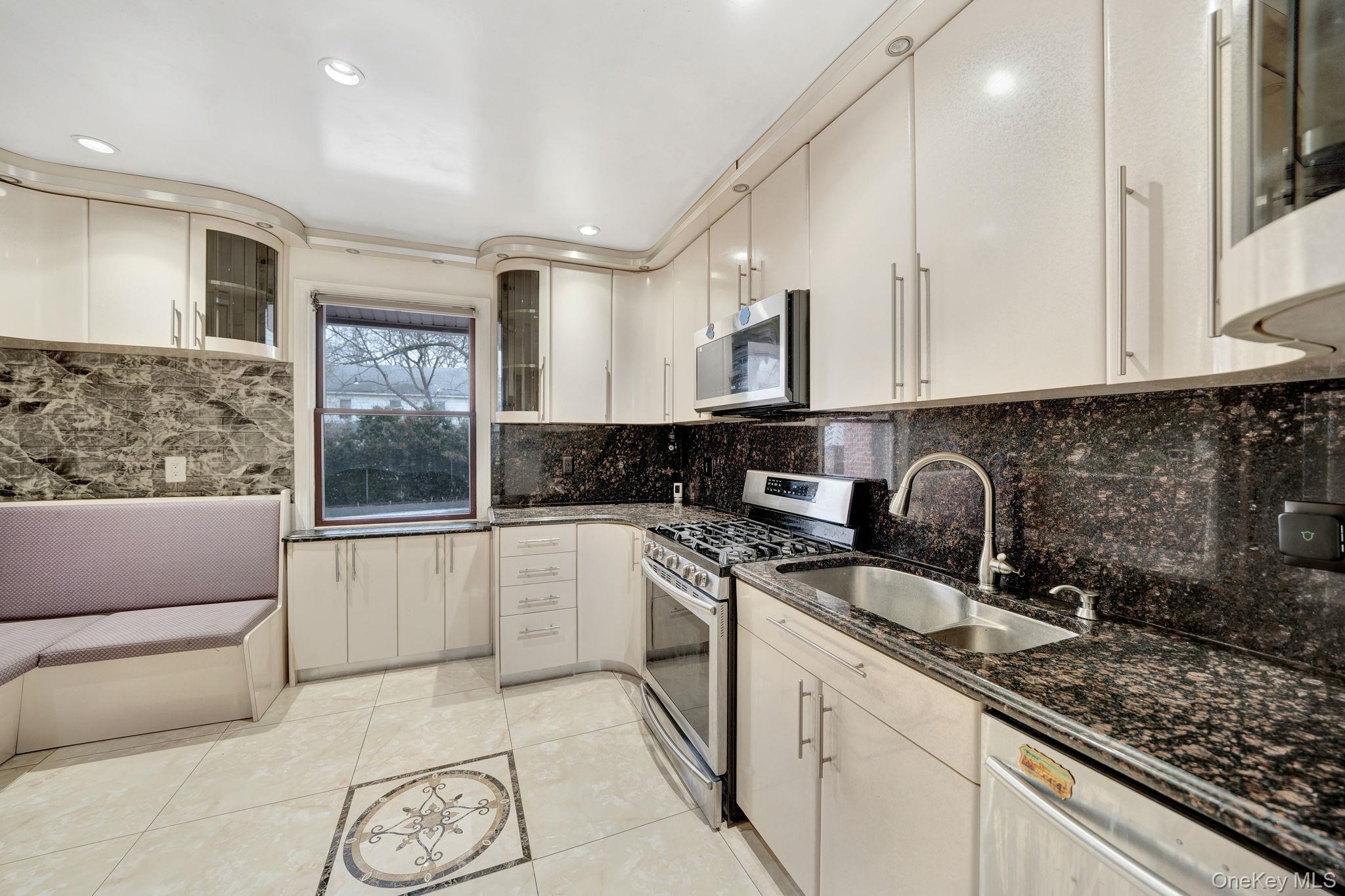 87-67 Chevy Chase Street Queens, NY 11432 - Photo 13 of 31 a kitchen with a sink dishwasher a stove and white cabinets with wooden floor