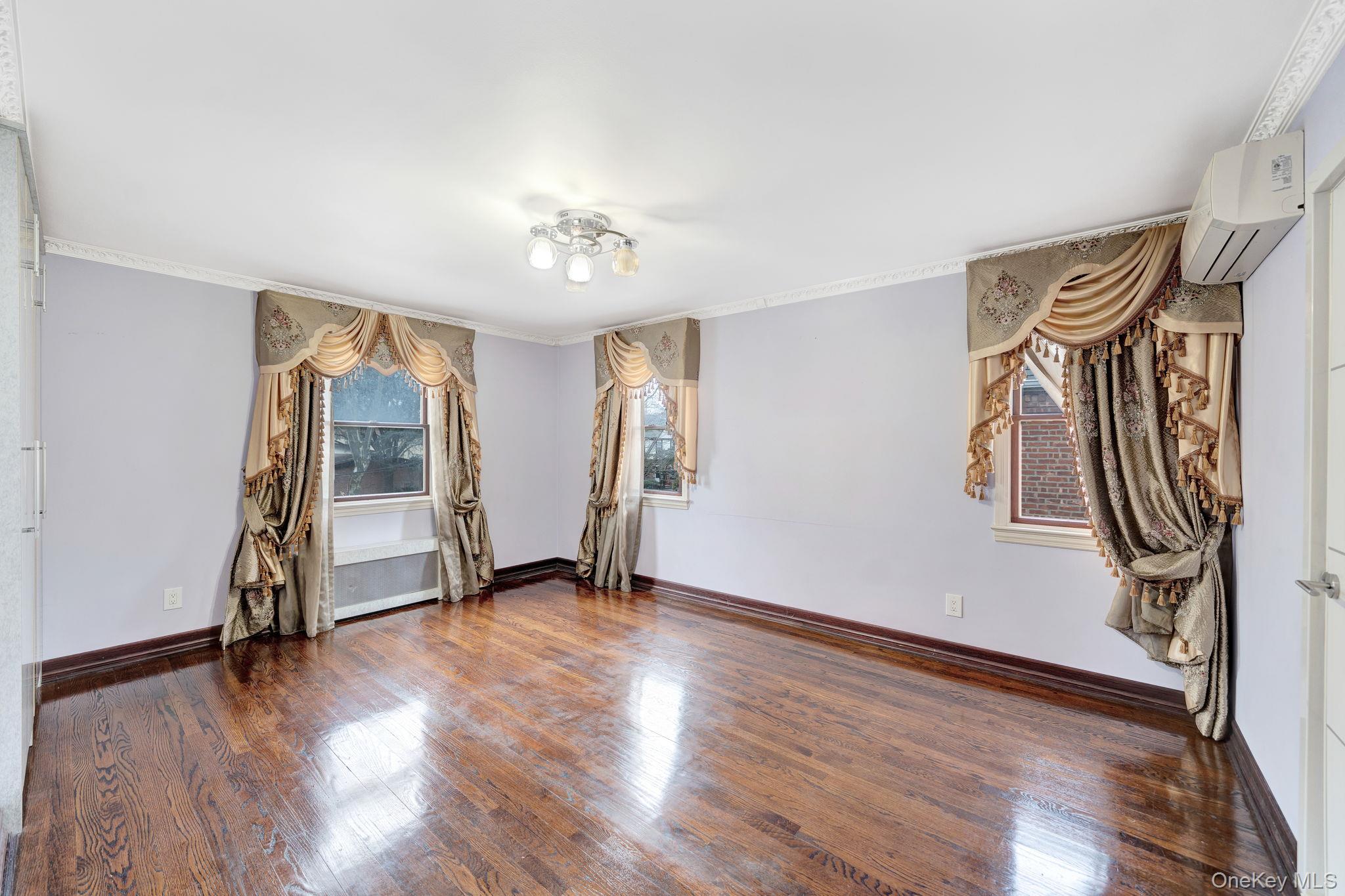 87-67 Chevy Chase Street Queens, NY 11432 - Photo 20 of 31 an empty room with wooden floor and windows