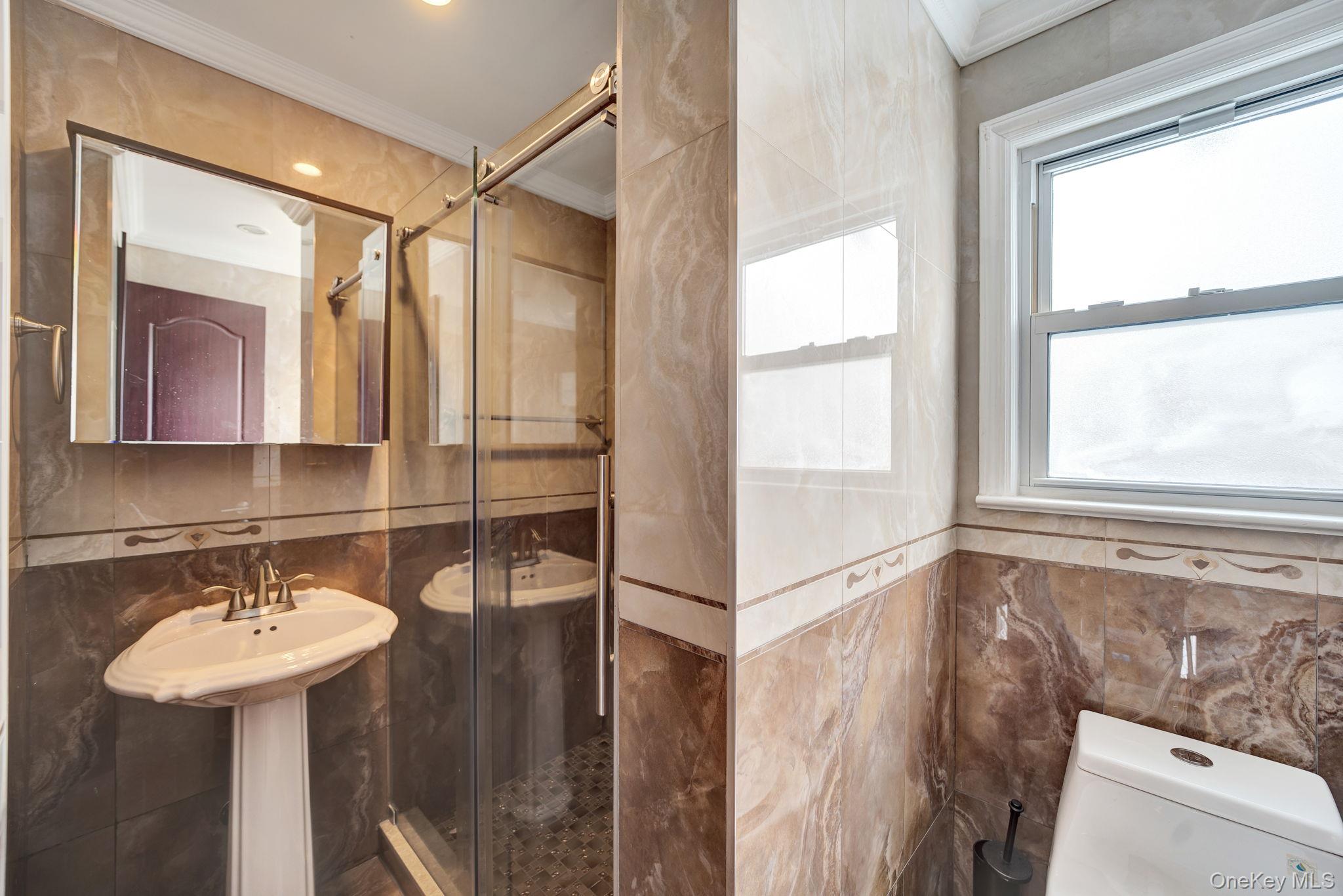 87-67 Chevy Chase Street Queens, NY 11432 - Photo 24 of 31 a bathroom with a sink and mirror with window