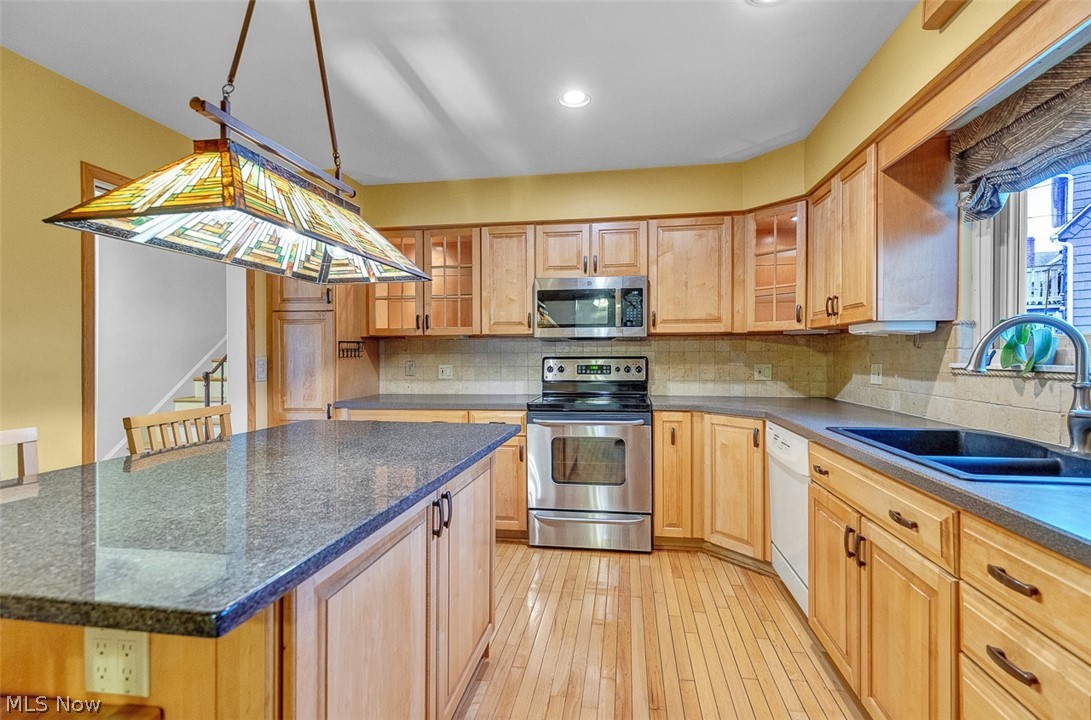 2990 Hampton Road Cleveland, OH 44120 - Photo 12 of 29 Kitchen featuring stainless steel appliances, glass fronted cabinets, tasteful backsplash, light wood-type flooring, and a kitchen bar