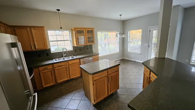 a kitchen with granite countertop a sink a counter space and stainless steel appliances