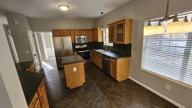 a kitchen with stainless steel appliances granite countertop a refrigerator a stove and a sink with wooden floor