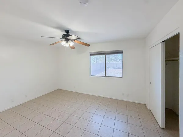 an empty room with a chandelier fan and windows