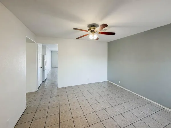 a view of an empty room and chandelier fan