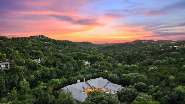 an aerial view of a house with a yard and trees all around