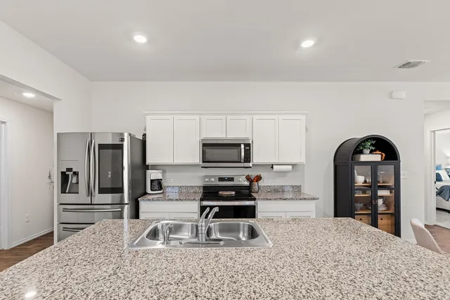 a kitchen with granite countertop a refrigerator and a stove top oven