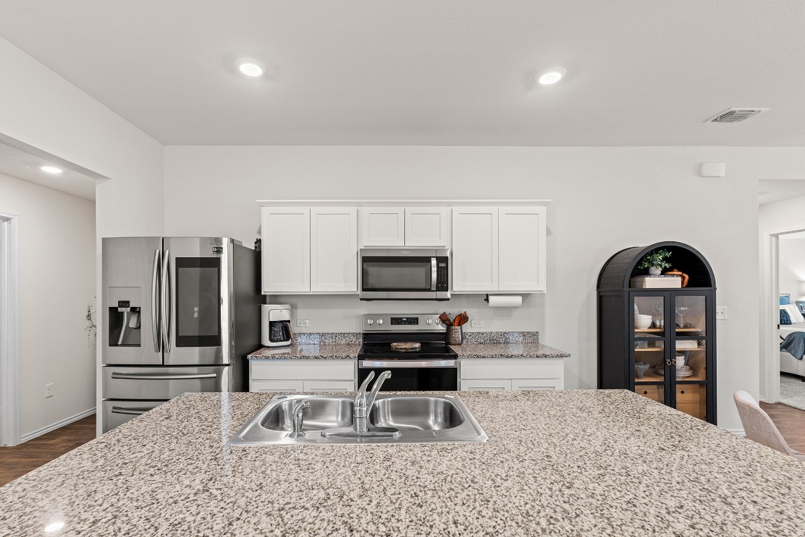 11817 Rush Lane Elgin, TX 78621 - Photo 6 of 30 a kitchen with granite countertop a refrigerator and a stove top oven