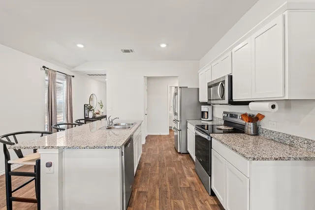 a kitchen with stainless steel appliances granite countertop a sink stove and refrigerator