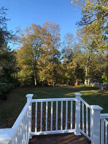 a balcony with wooden floor and yard in the back