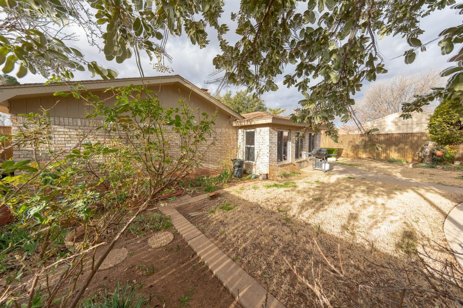 4424 76th Street Lubbock, TX 79424 - Photo 25 of 27 a backyard of a house with large trees and wooden fence