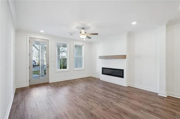 a view of an empty room with wooden floor fireplace and a window