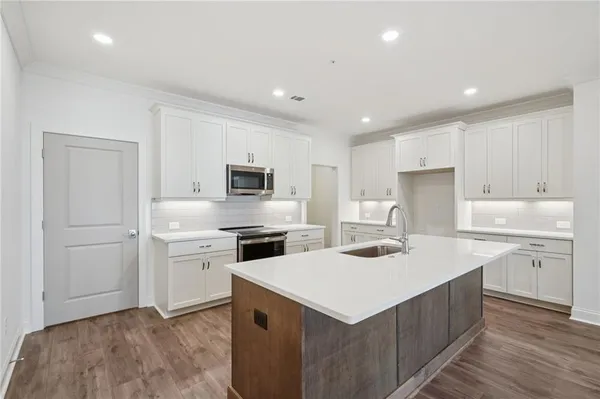 a kitchen with a sink a stove a refrigerator and white cabinets