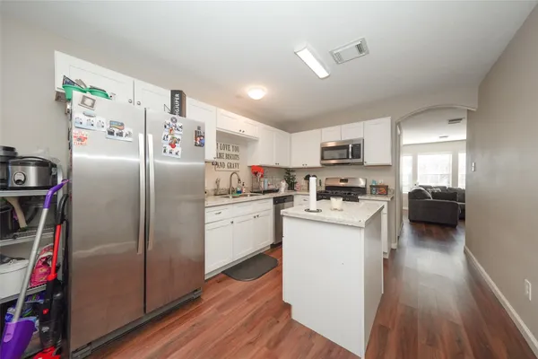 a kitchen with refrigerator a microwave and white cabinets