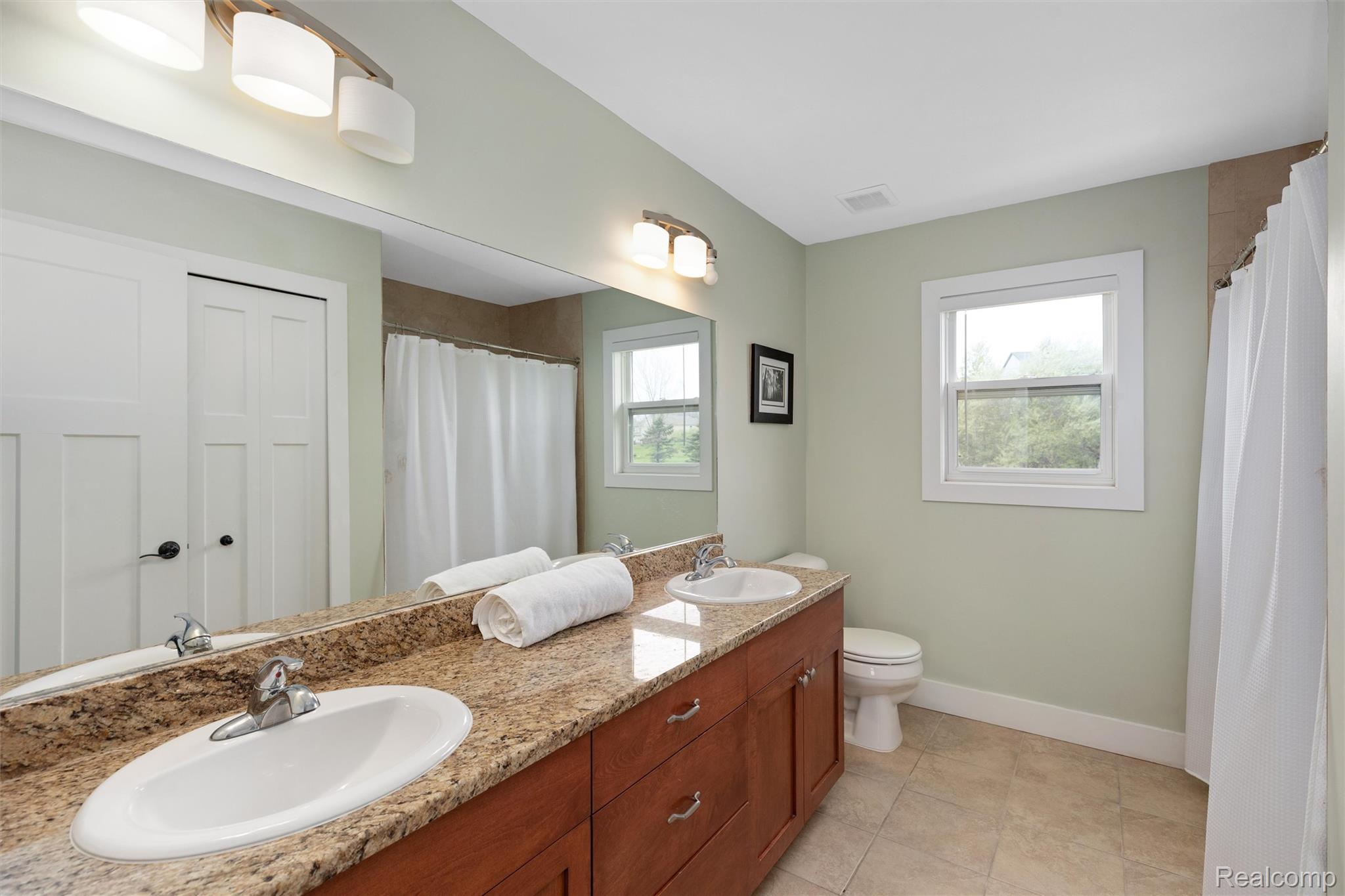 1016 West Snell Road Rochester, MI 48306 - Photo 21 of 35 Spacious bathroom featuring a double vanity with polished chrome fixtures, ample storage cabinetry, and a large mirror