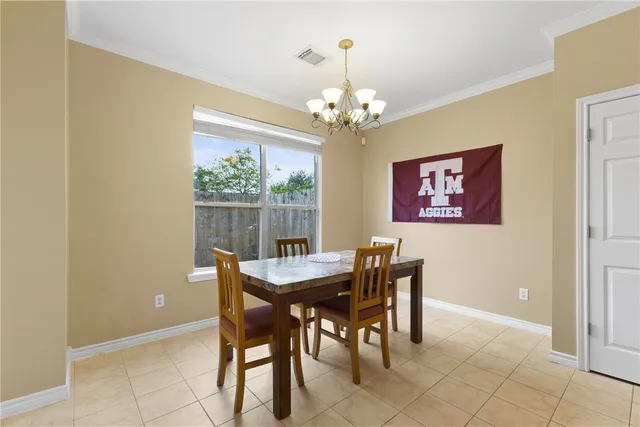 a view of a dining room with furniture a chandelier and a window