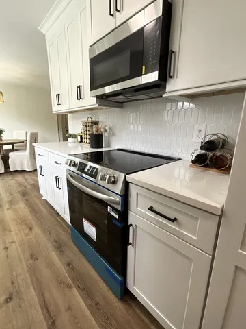 a kitchen with stainless steel appliances white cabinets and a stove top oven