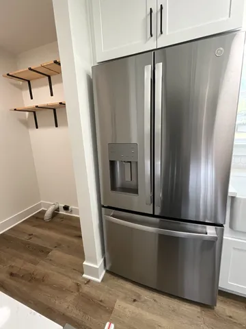 a view of a refrigerator in kitchen and an empty room
