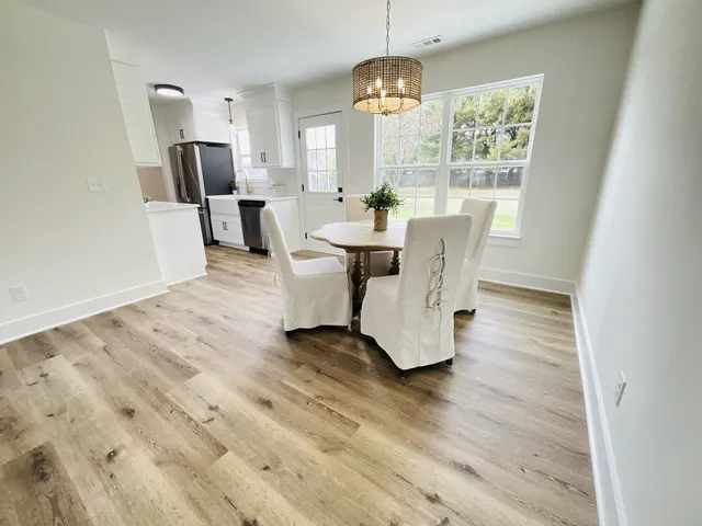 a view of a dining room with furniture a chandelier and wooden floor