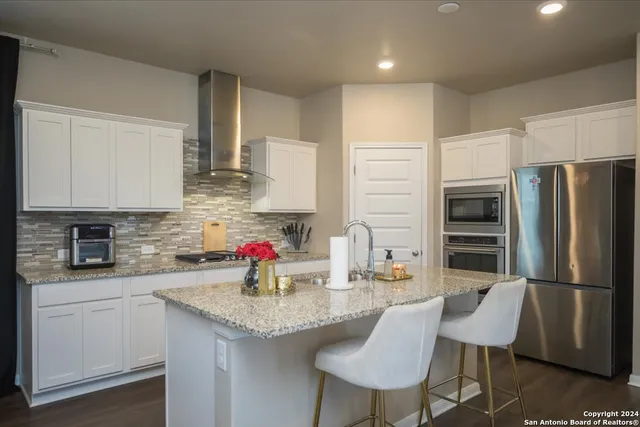 a kitchen with stainless steel appliances granite countertop a sink refrigerator and cabinets