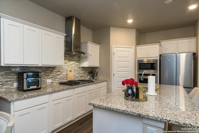 a kitchen with stainless steel appliances granite countertop a sink refrigerator and cabinets