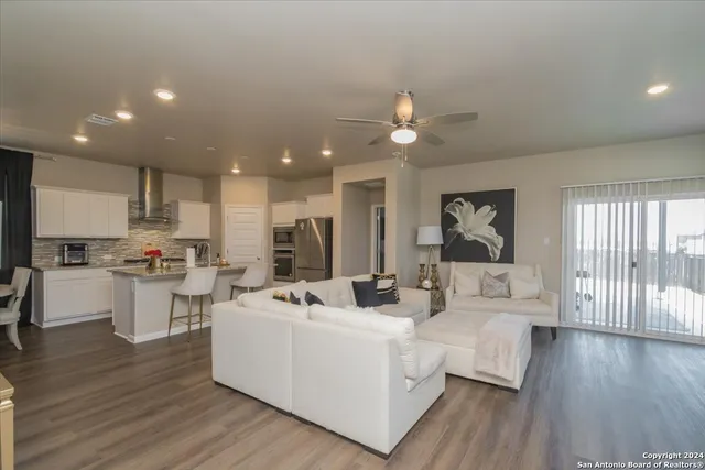 a living room with couches and kitchen view with wooden floor