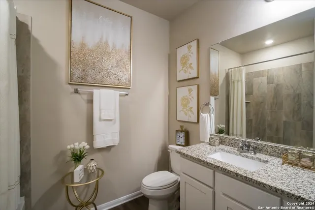 a bathroom with a granite countertop sink a toilet and a mirror