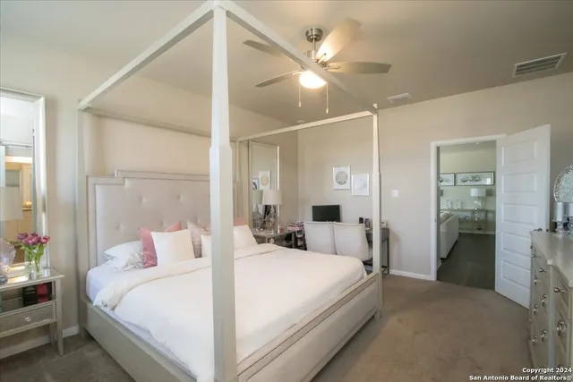 a bedroom with a large bed and a chandelier fan