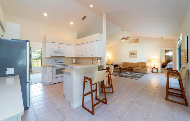 a kitchen with a refrigerator a oven a sink and chairs