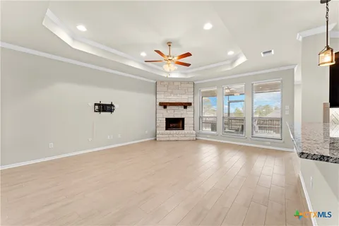 an empty room with wooden floor fireplace and windows