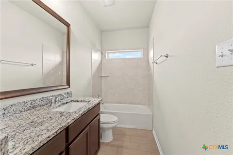 a bathroom with a granite countertop sink a toilet and shower