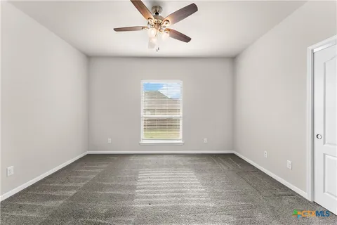 an empty room with a window and a fan