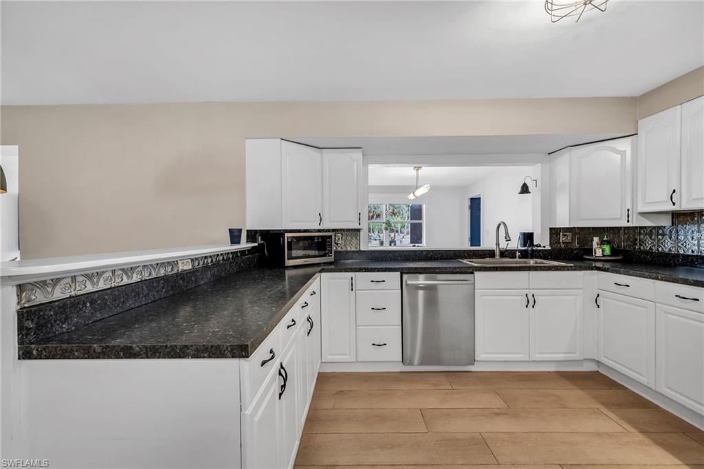 1840 23rd Street Southwest Naples, FL 34117 - Photo 18 of 50 Kitchen featuring white cabinetry, stainless steel appliances, backsplash, light wood plank porcelain tile flooring
