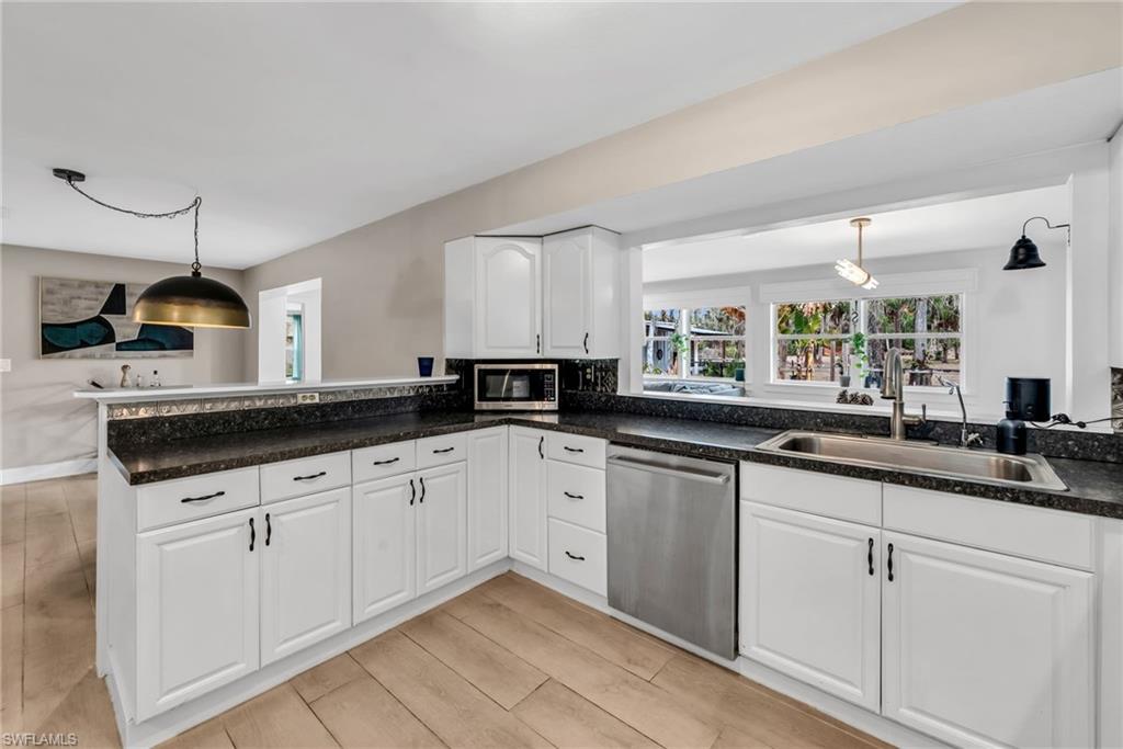 1840 23rd Street Southwest Naples, FL 34117 - Photo 19 of 50 Kitchen featuring white cabinetry, stainless steel appliances, backsplash, light wood plank porcelain tile flooring